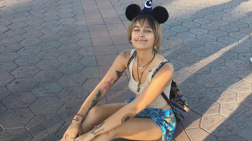 Paris Jackson, in Disneyland, sitzt auf dem Boden und lächelt