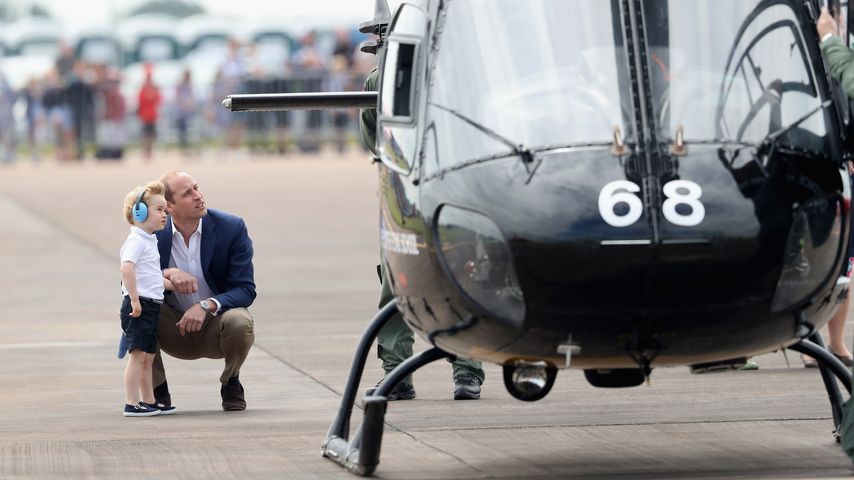 Prinz William hockt mit seinem Sohn Prinz George vor einem Hubschrauber